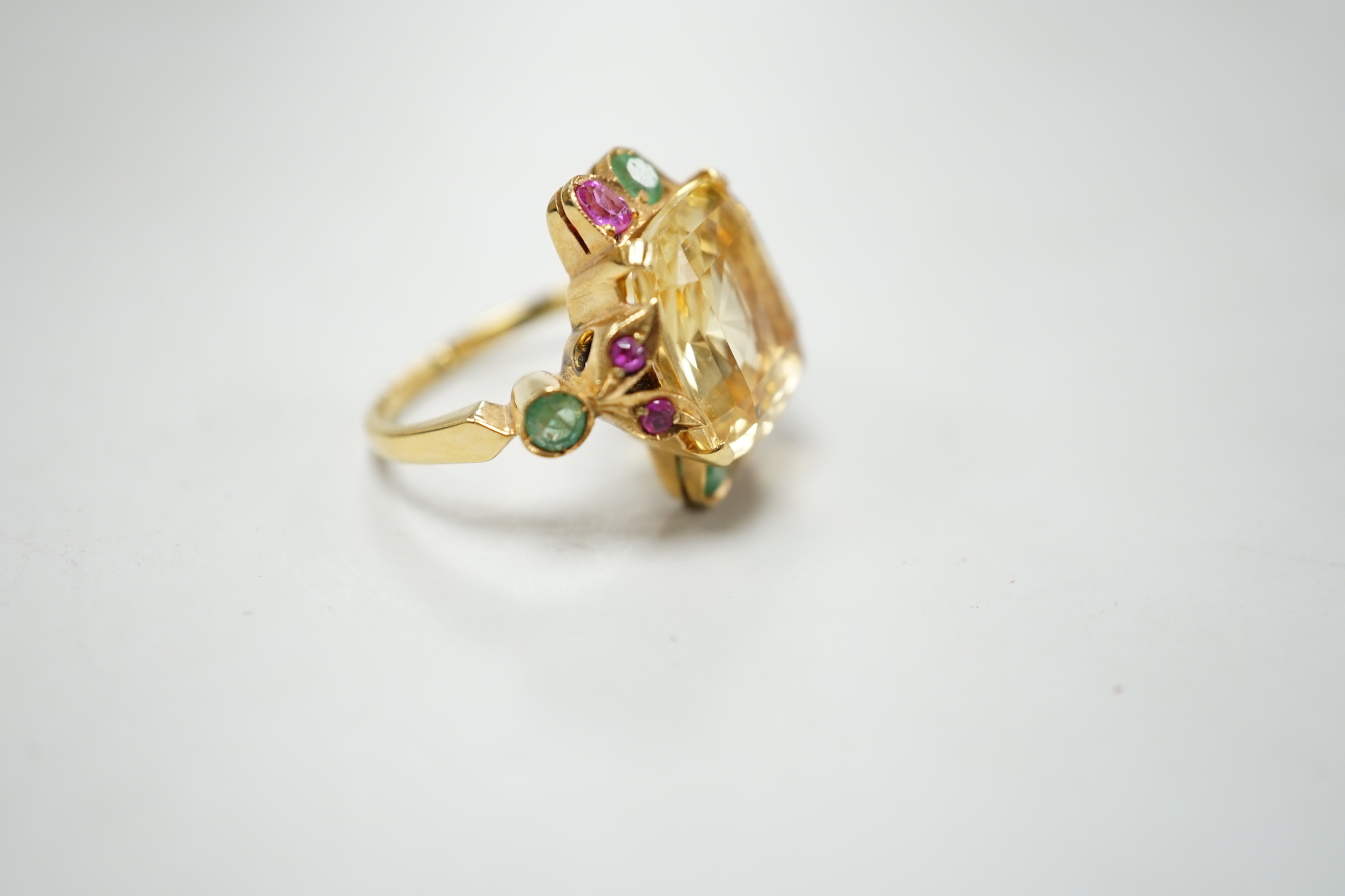 An 18ct and single stone yellow sapphire set dress ring, with emerald and ruby set setting and shoulders, size M, gross weight 9.4 grams.